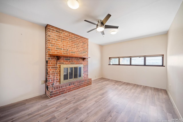 unfurnished living room with ceiling fan, a fireplace, and light hardwood / wood-style flooring