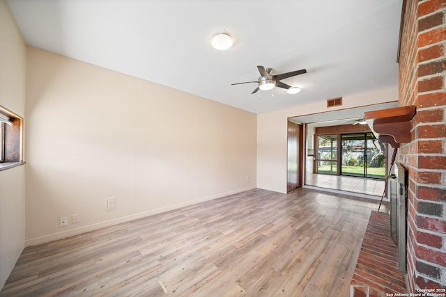 interior space featuring ceiling fan, a brick fireplace, and light wood-type flooring