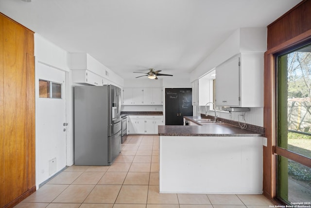 kitchen with appliances with stainless steel finishes, sink, white cabinets, light tile patterned floors, and kitchen peninsula