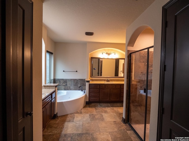 bathroom with vanity, separate shower and tub, and a textured ceiling