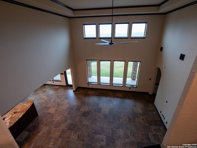 unfurnished living room featuring a high ceiling, crown molding, and ceiling fan