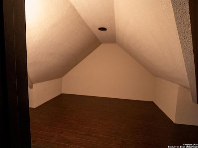 bonus room featuring dark hardwood / wood-style floors, vaulted ceiling, and a textured ceiling