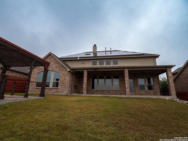 rear view of house with a lawn and solar panels