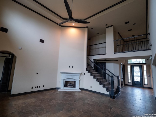 unfurnished living room featuring a towering ceiling and ceiling fan