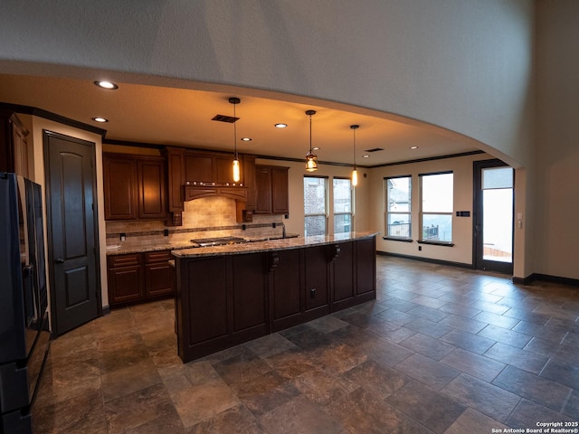 kitchen featuring a large island, decorative light fixtures, dark brown cabinets, and black fridge