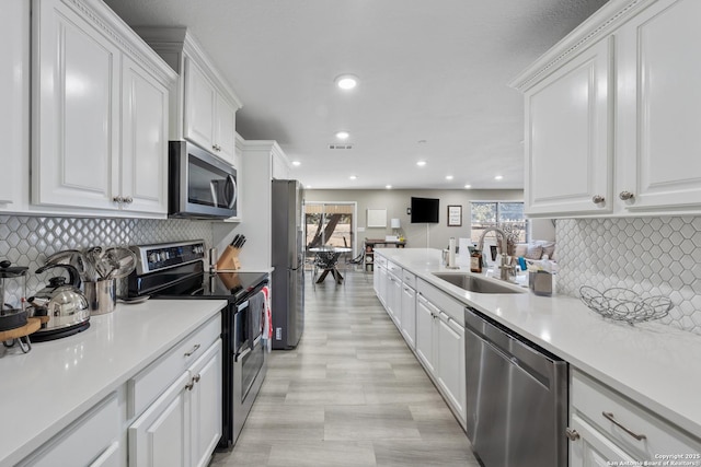 kitchen with backsplash, stainless steel appliances, sink, and white cabinets