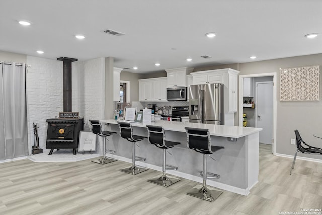 kitchen with stainless steel appliances, white cabinetry, a kitchen bar, and kitchen peninsula