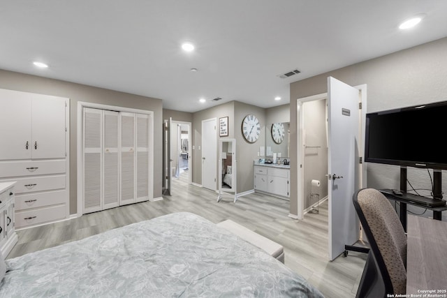 bedroom with ensuite bath and light hardwood / wood-style flooring