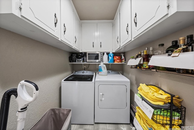 laundry area featuring cabinets, washing machine and dryer, and light hardwood / wood-style flooring