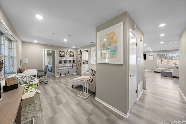 hallway featuring light hardwood / wood-style flooring and a barn door