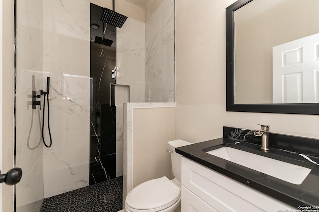 bathroom with vanity, a tile shower, and toilet