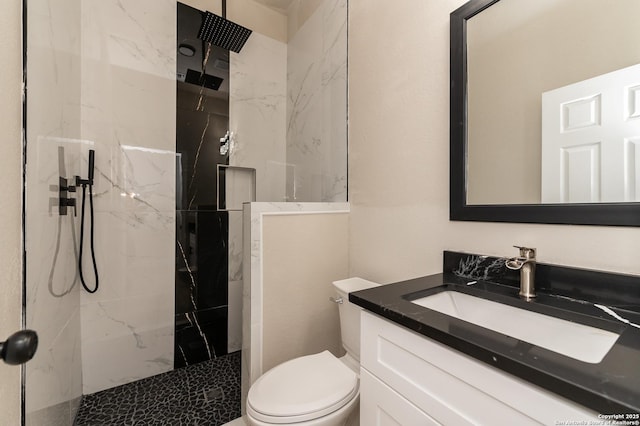 bathroom with vanity, toilet, and a tile shower