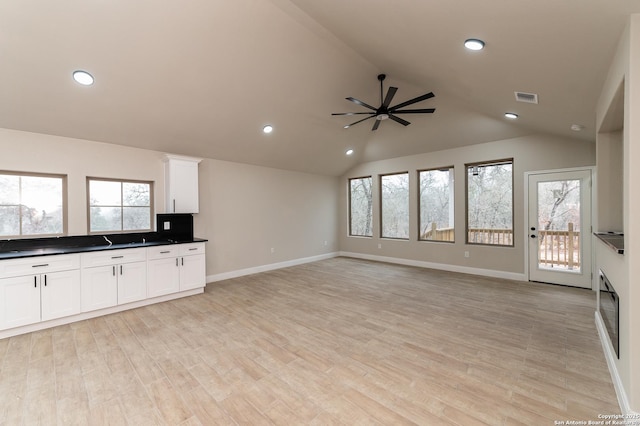 kitchen featuring ceiling fan, vaulted ceiling, white cabinets, and light wood-type flooring