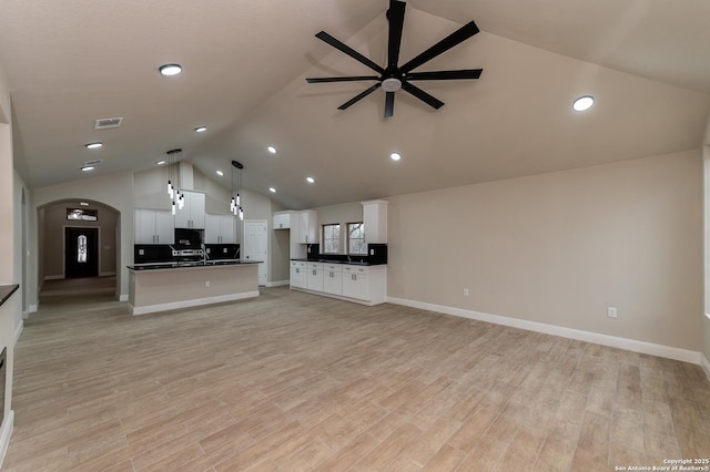 unfurnished living room with light hardwood / wood-style flooring, high vaulted ceiling, and ceiling fan