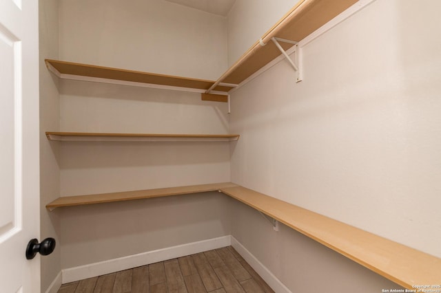 spacious closet featuring hardwood / wood-style flooring and built in desk