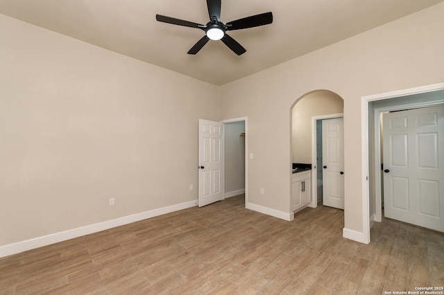 unfurnished bedroom featuring ceiling fan, ensuite bathroom, and light wood-type flooring