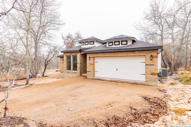 view of front of property featuring a garage and central air condition unit