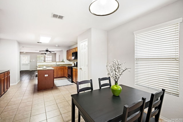 dining space featuring light tile patterned floors, sink, and ceiling fan