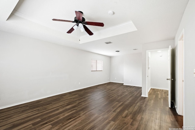 empty room featuring dark hardwood / wood-style floors, ceiling fan, and a tray ceiling