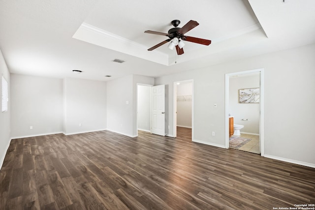 unfurnished bedroom with crown molding, dark hardwood / wood-style flooring, a raised ceiling, and a spacious closet