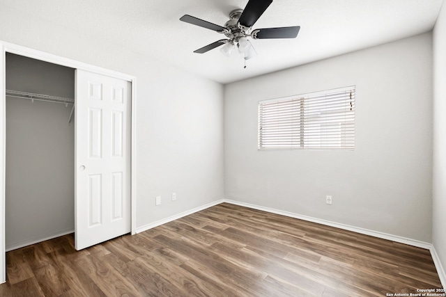 unfurnished bedroom featuring dark wood-type flooring, ceiling fan, and a closet