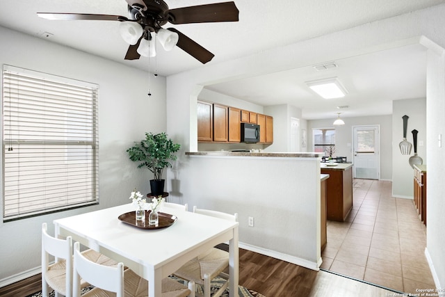 dining space with ceiling fan and light wood-type flooring