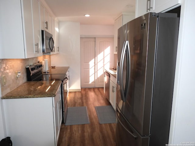 kitchen featuring dark hardwood / wood-style floors, white cabinets, backsplash, dark stone counters, and stainless steel appliances