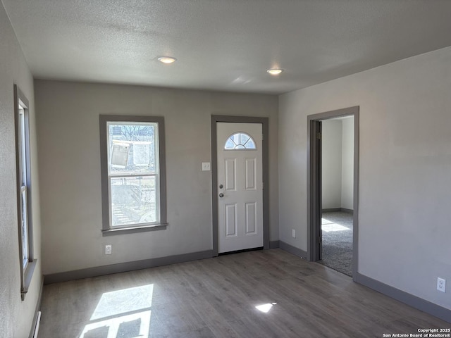 foyer entrance with light hardwood / wood-style floors and a textured ceiling