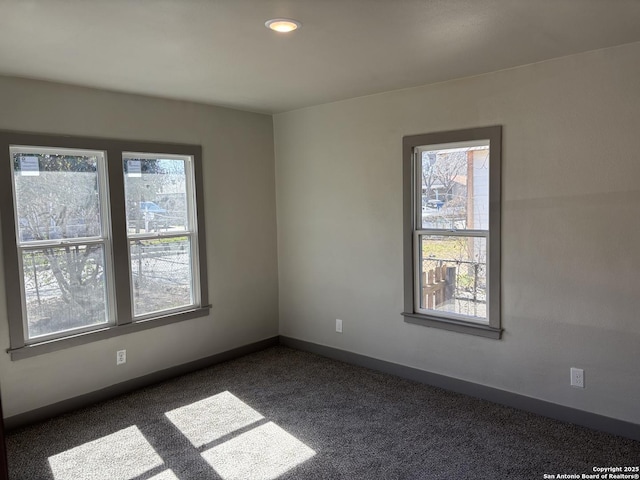 spare room featuring a healthy amount of sunlight and dark colored carpet