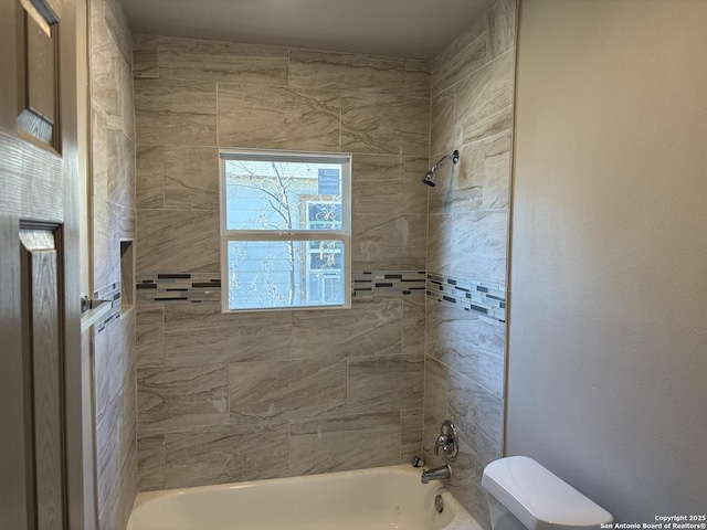 bathroom with tiled shower / bath combo and toilet