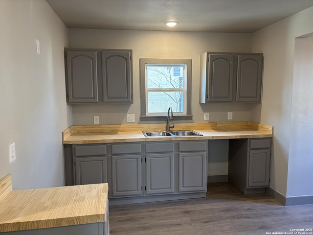 kitchen with butcher block countertops, sink, gray cabinetry, and dark wood-type flooring