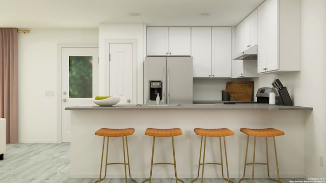 kitchen with white cabinetry, stainless steel refrigerator with ice dispenser, a kitchen breakfast bar, and kitchen peninsula