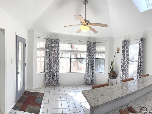 interior space featuring ceiling fan, plenty of natural light, vaulted ceiling, and light tile patterned floors