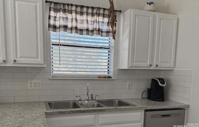 kitchen featuring sink, light stone counters, stainless steel dishwasher, white cabinets, and backsplash