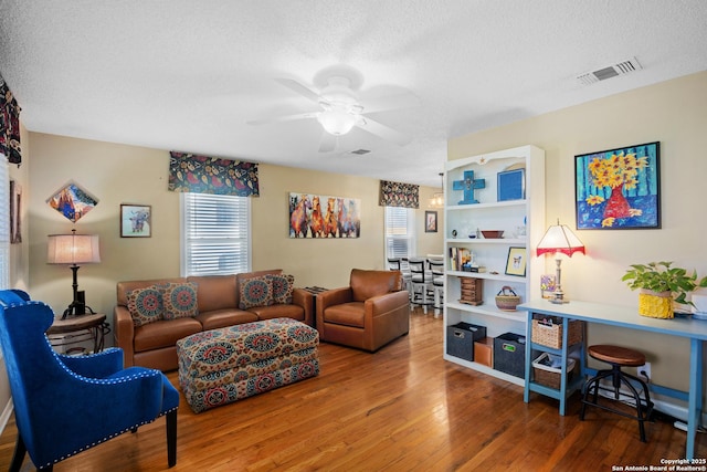 living room with ceiling fan, hardwood / wood-style floors, and a textured ceiling