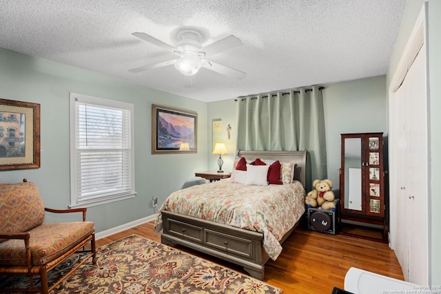 bedroom featuring wood-type flooring, ceiling fan, a textured ceiling, and a closet