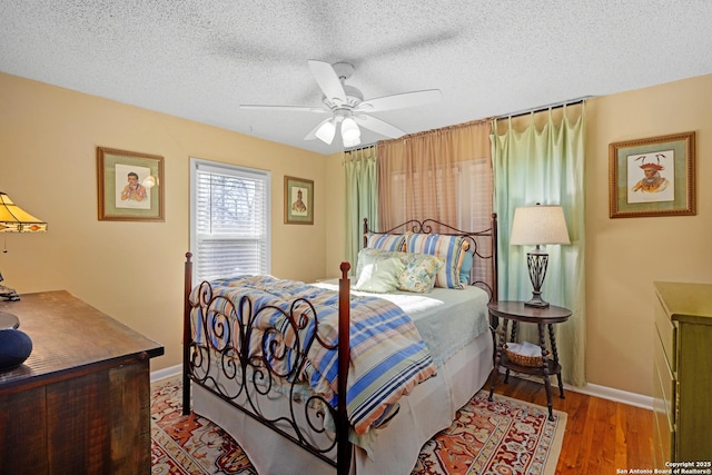 bedroom featuring ceiling fan, hardwood / wood-style floors, and a textured ceiling