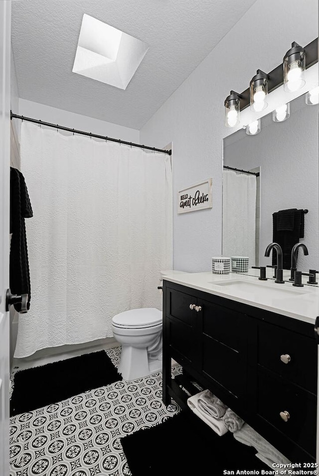 bathroom featuring vanity, a textured ceiling, tile patterned floors, and toilet