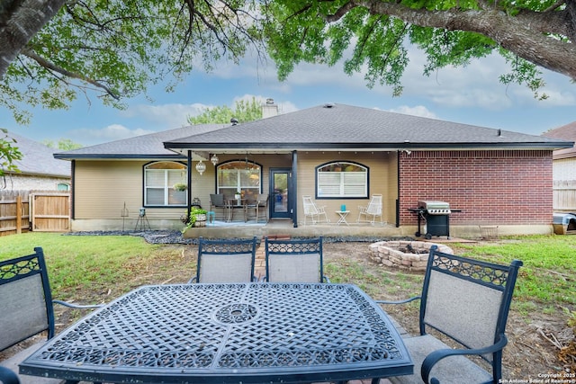 rear view of house featuring a yard, a patio, and an outdoor fire pit