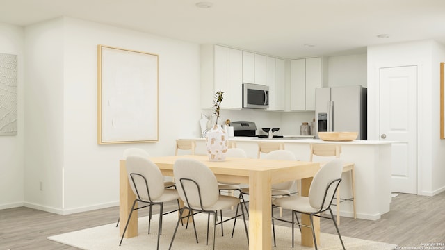 kitchen with stainless steel appliances, white cabinetry, a kitchen bar, and light wood-type flooring