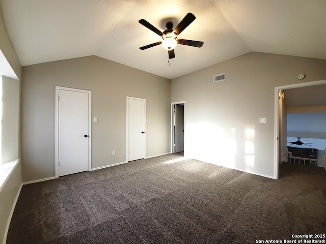 unfurnished bedroom with lofted ceiling, dark carpet, and ceiling fan