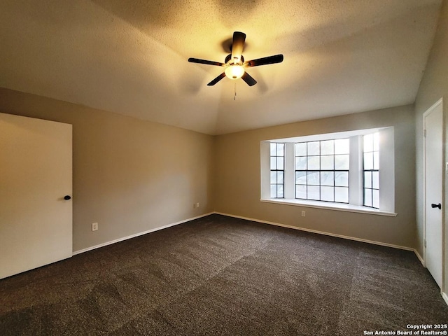 empty room with vaulted ceiling, ceiling fan, a textured ceiling, and dark carpet