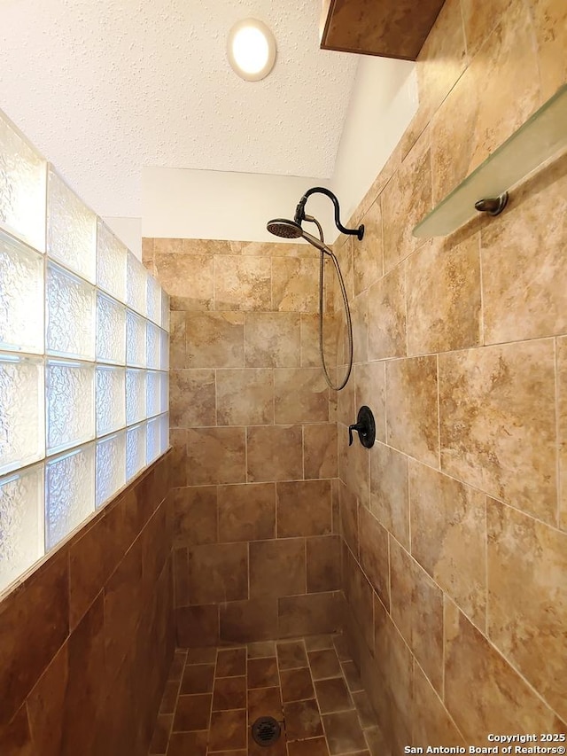 bathroom featuring a tile shower and a textured ceiling