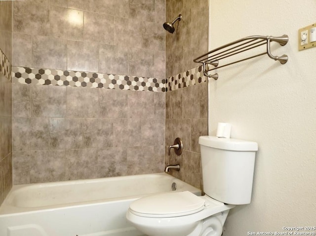 bathroom with tiled shower / bath combo and toilet