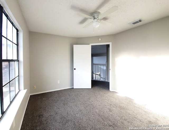 carpeted empty room with ceiling fan and a textured ceiling