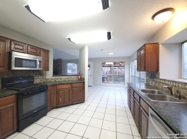 kitchen with sink, light tile patterned floors, stainless steel appliances, tasteful backsplash, and a textured ceiling