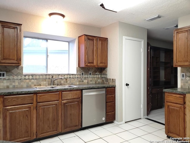 kitchen with sink, backsplash, stainless steel dishwasher, light tile patterned floors, and a textured ceiling