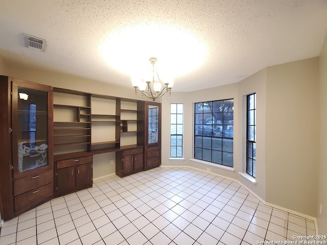 interior space featuring built in desk, a notable chandelier, and a textured ceiling