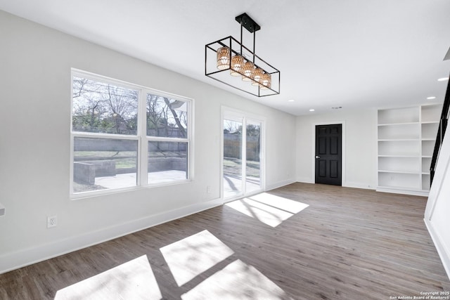 unfurnished dining area featuring hardwood / wood-style floors, built in features, and a wealth of natural light