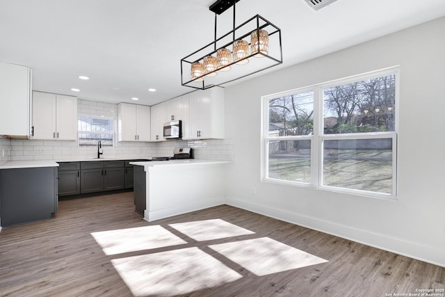 kitchen with gray cabinets, appliances with stainless steel finishes, decorative light fixtures, white cabinets, and backsplash